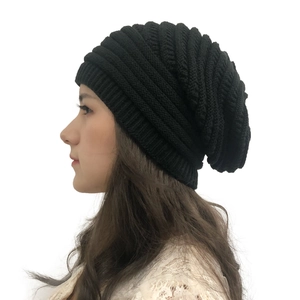 Close-up of a black ribbed knit beanie worn by a model against a white background