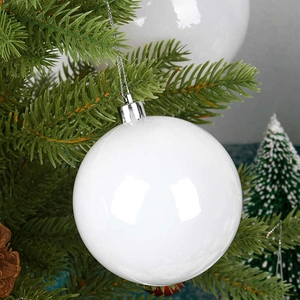 Glossy white Christmas ball ornament hanging on a pine tree branch with silver string