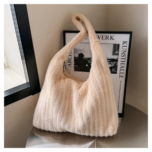 Close-up of a cream fuzzy tote bag leaning against a minimalist frame on a metal desk