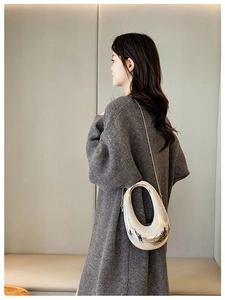 Silver oval cutout metallic clutch bag styled with a sleek metal chain on model