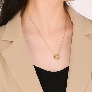 Close-up of interlocking triple ring gold necklace on woman wearing a beige blazer