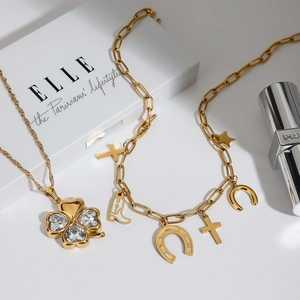 Golden stainless steel clover necklace with heart-shaped gems and charms on white background