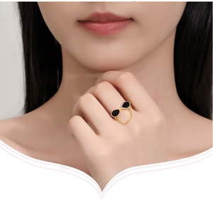 Detailed view of a gold chain ring with black water drop accents worn by a model