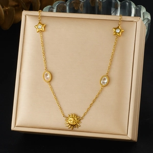 Detail of gold sun face pendant and star charms on necklace in a luxury gift box