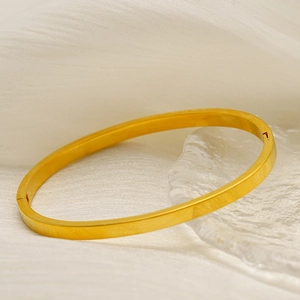 Polished 18k gold plated stainless steel minimalist bangle on soft silk fabric background