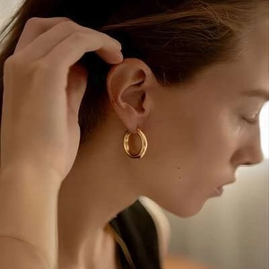 Polished 18k gold plated stainless steel thick hoop earrings worn by a model