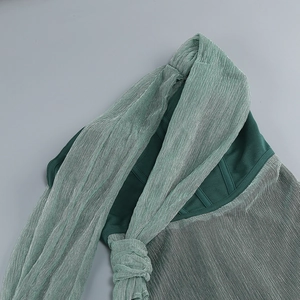 Détail du tissu vert scintillant montrant une texture plissée fine et un fini métal