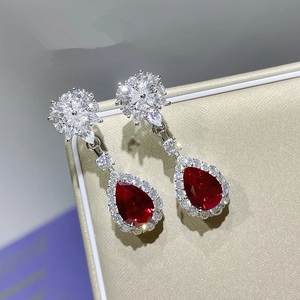 Macro shot of elegant pear-shaped red gemstone earrings with sparkling diamond halo