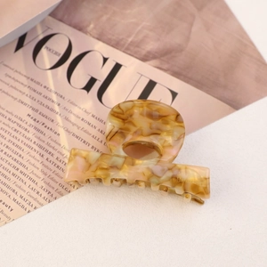 Macro detail of amber marble acetate hair claw showing smooth texture and inner branding