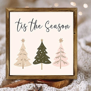 Close-up of wooden frame with 'tis the Season' text and Christmas tree icons on a beige background