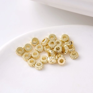 Dettaglio di perline distanziatrici dorate a forma di ingranaggio su ceramica bianca per DIY