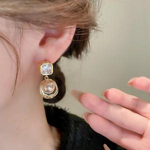 Vintage gold earrings with cubic zirconia and round pearls shown on model's ear