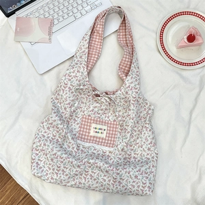 Detailed close-up of pink floral tote bag with lace-trimmed plaid pocket and logo