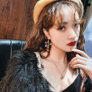 Detailed shot of hollow star-shaped earrings with colorful rhinestones on a female model