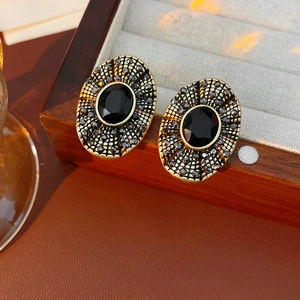 Dettaglio ravvicinato di orecchini vintage ovali dorati con pietra nera e strass