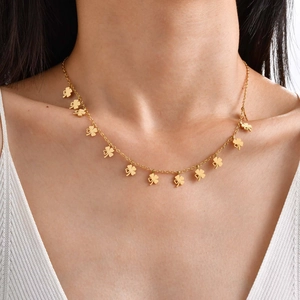 Nahaufnahme der goldenen Edelstahlkette mit mehreren Kleeblatt-Anhängern am Hals