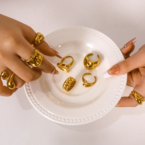 Chunky gold irregular heart rings and braided metal bands set on a white tray