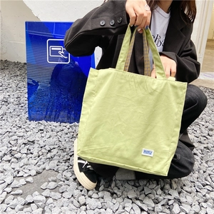 Detalle del bolso de lona verde claro con costuras de cuadros marrones en las asas