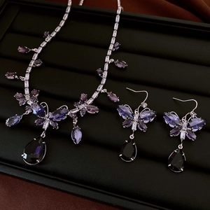 Detailansicht eines silbernen Schmetterling-Schmucksets mit lila Kristallen und Tropfen