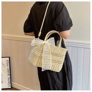Detailed view of beige straw handbag with white lace bow and adjustable crossbody strap