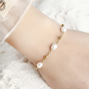 Exquisite gold stainless steel beaded pearl bracelet worn on wrist with lace backdrop