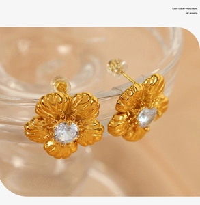 Macro detail of vintage floral stud earrings featuring clear crystal and golden petals