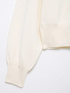 Detailed macro view of cream knit cardigan featuring ribbed cuffs and fine stitch texture