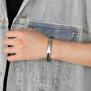 Close-up of men's black woven bracelet with silver steel accents on denim jacket