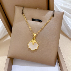 Dettaglio della collana dorata con stella marina e conchiglia su portagioie beige