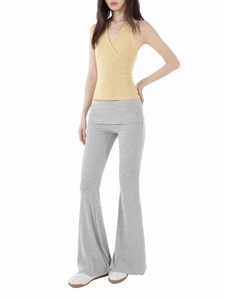 Detail of yellow knit halter top and grey high waist flared trousers on a model