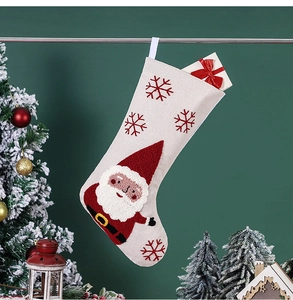 Détail de chaussette de Noël avec broderie Père Noël suspendue sur mur vert foncé