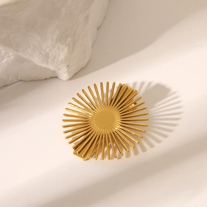 Barrette dorée artistique en forme de soleil sur fond blanc avec pierre texturée