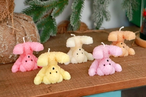 Handcrafted upside-down bear candles in five pastel colors on a rustic wooden table