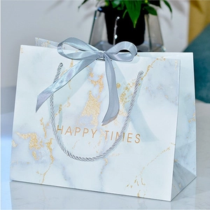 Detail of marble pattern gift bag with grey ribbon bow and golden Happy Times text