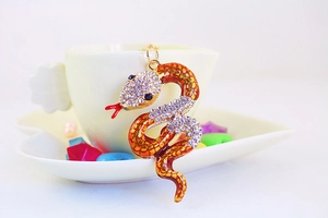 Detailed macro view of the rhinestone-studded snake keychain on a white ceramic cup