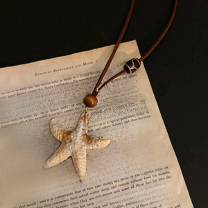 Vintage starfish pendant necklace with wooden beads on a retro book background