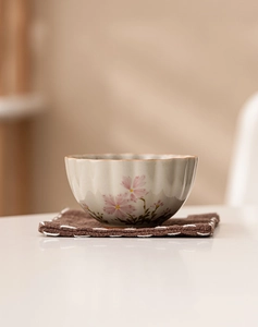 Macro detail of daisy floral ceramic teacup with a woven coaster on a minimalist background