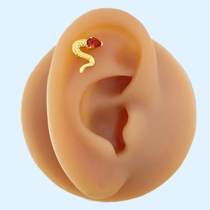 Snake helix earring in gold with a red pear-shaped zircon on a silicone ear model