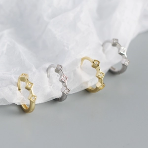 Macro shot of gold and silver geometric diamond-shaped earrings with clear crystals