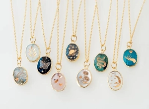 Detailed macro view of multiple gold stainless steel pendants with diverse artistic motifs