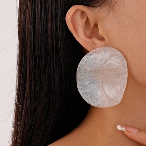 Detail shot of large ivory resin stud earrings with a textured pearl-like finish