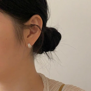 Close-up of minimalist silver zircon earrings with brushed texture on a model's ear