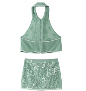 Detail of green two-piece set featuring intricate white floral embroidery on a mini skirt
