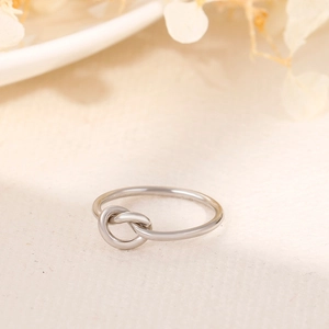 Detailed view of silver knot ring on soft white fabric with dried flower accents