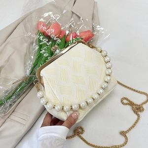 Close-up of cream woven shell bag featuring pearl handle and gold clasp detail