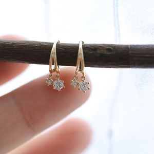 Macro detail van gouden geometrische zirkoon oorbellen hangend aan een houten takje