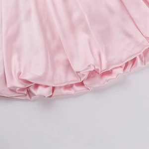 Detail of pink satin mini dress showing glossy fabric and pleated bubble hem finish