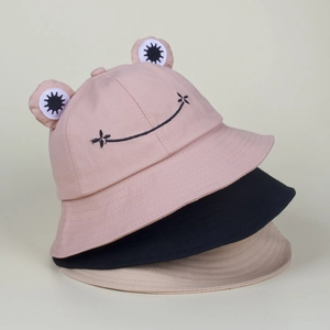 Close-up of pink black and beige frog bucket hats with 3D eyes and smiley embroidery