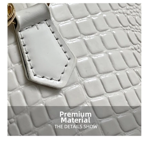 Detailed close-up of white croc-embossed leather texture and gold hardware on handbag