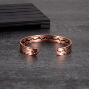 Adjustable open copper magnetic bracelet with black wave pattern on stone background